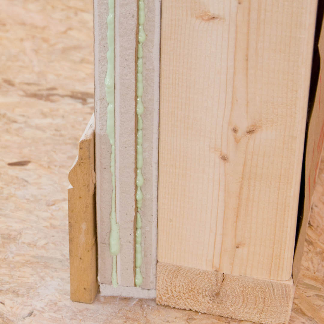 A cutaway of a wall with two layer of Green Glue on one side.